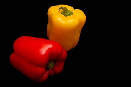 Tasty red and yellow pepper in black background