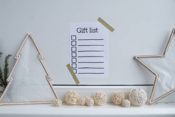 istock Holiday preparation paper note with GIFT LIST checklist text. Vision board wall with cozy minimalistic handmade new year Christmas decor Low key festive celebration 2149464415