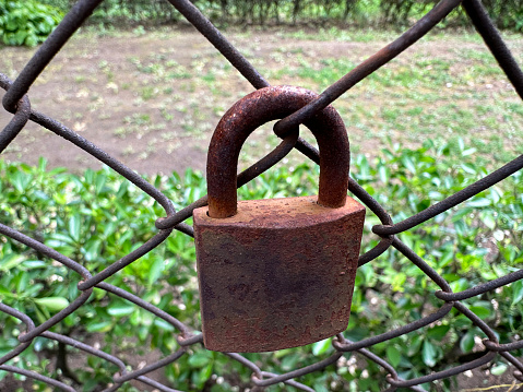 Rusty old padlock on a chainlink fence