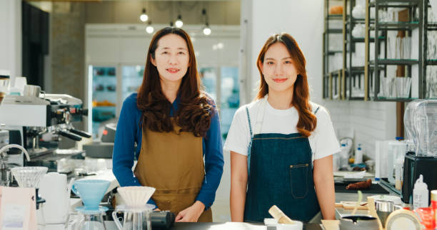 istock Two happy female entrepreneurs, a mentor and her trainee, pose with confidence at their successful and sustainable coffee shop. Small business owner. 2149476195