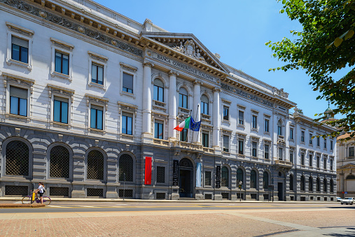 Milan, Italy - June 24, 2023:  Banca Commerciale Italiana (BCI palace) in Milano, on Piazza della Scala square. Italian and European Union flags on historical building.