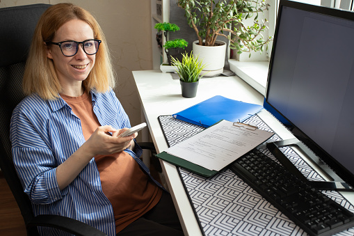 pregnant woman at the workplace with a phone, online shopping, ordering medicines, delivery of goods for maternity