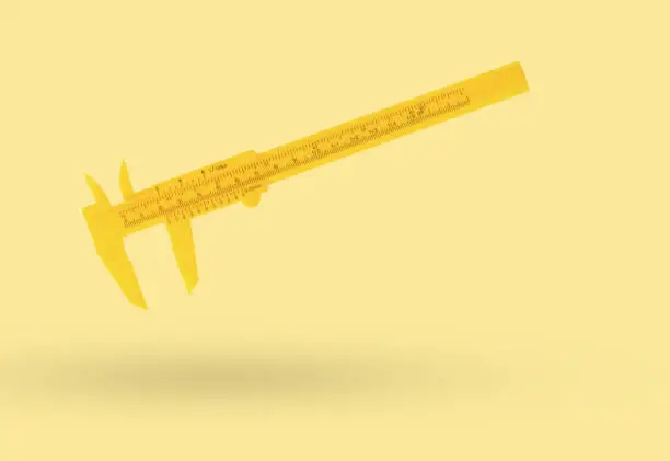 Classic yellow caliper on a yellow background. A tool for accurate measurement of dimensions.