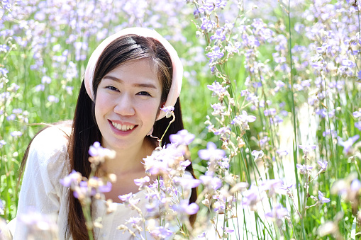 Beautiful Asian woman is smiling and relaxing in blooming purple Murdannia giganteum flowers field