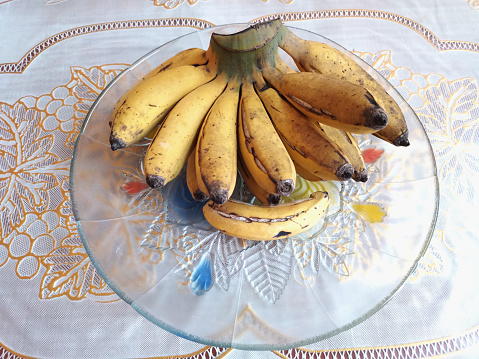 Organic yellow bananas in a white plate, ripe and abundant. Freshness and nutrition