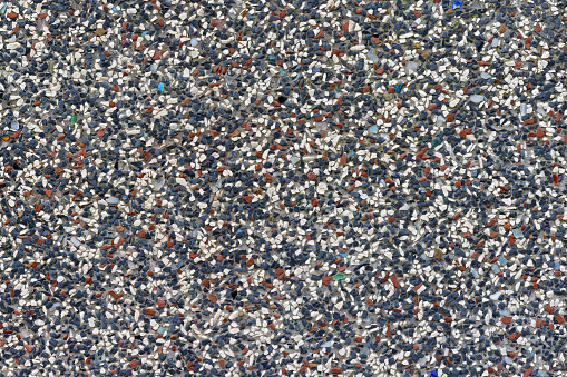closeup background view of a colored plaster area, consisting of white, dark blue and red decor stones in random arrangement