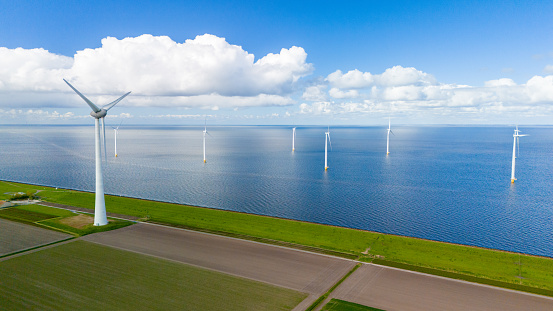 A wind farm filled with turbines in the ocean of the Netherlands, harnessing the power of the wind to generate clean energy. in the Noordoostpolder Netherlands, windmill turbines at sea