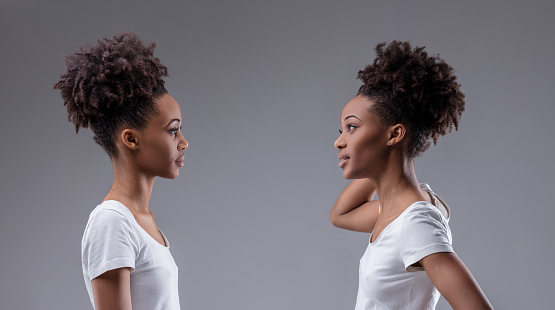 Self-doubt and scrutiny interplay in the stance of a young black woman evaluating her reflection