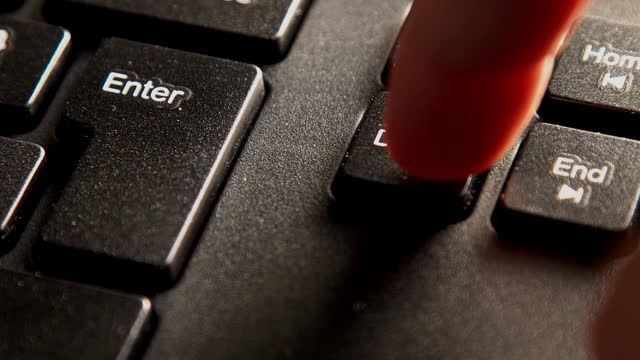 Finger Pressing Delete Key On A Black Computer Keyboard
