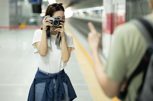 A couple female backpacker taking a photo with her camera at the railway station.