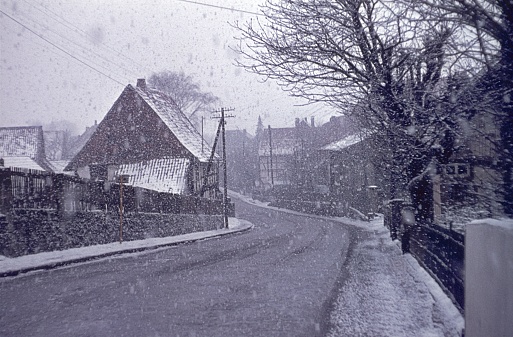 Germany, 1969. Village street with the beginning of snowfall in winter.