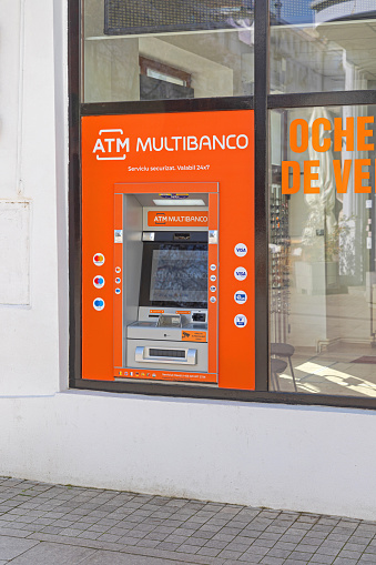 Craiova, Romania - March 16, 2024: Bright Orange Multibanco Bank Atm Cash in Store Window Town Centre.