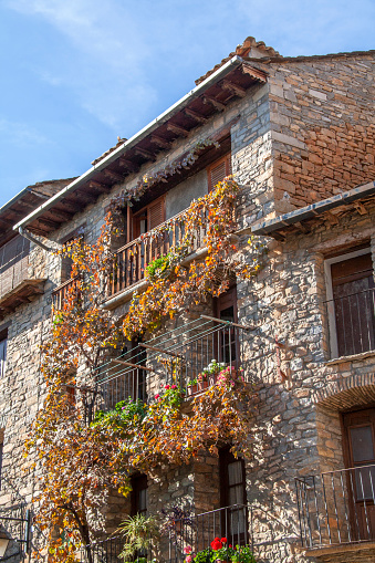 Ainsa. Stone facades of medieval houses with flower-covered balconies,