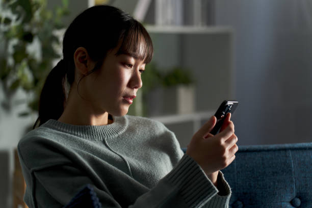 スマホを見ている憂鬱な女性 - 不眠症 日本人 ストックフォトと画像