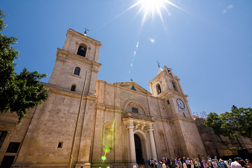 Valletta, Malta - 17 June 2023: Facade of Valletta Cathedral and tourists on a sunny day, Malta.