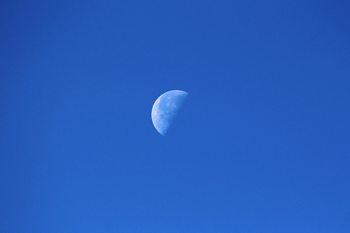 The Moon as Earths only natural satellite clearly visible in its Waning gibbous Moon phase on clear blue sky background early in the morning of warm autumn day