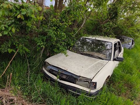 Car left in overgrown grass to rust