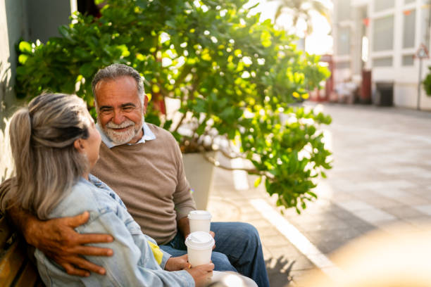 istock Senior man talking with wife on bench outdoors 2149509677