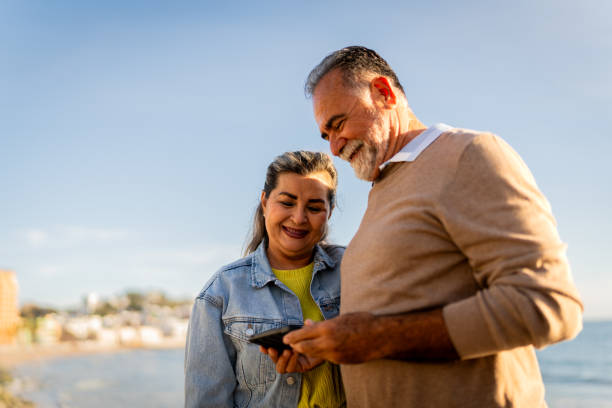 istock Senior couple using mobile phone on beach coastline 2149509762