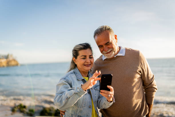 istock Senior couple using mobile phone on beach coastline 2149509768