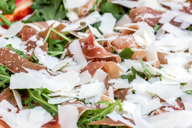 Close-up pizza, parmesan cheese, prosciutto, rocket.