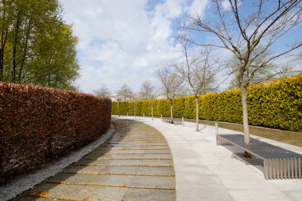 City park Krasnodar. An artificial fast-flowing river with granite banks flows around an evergreen hedge with a seating area. Public landscape Galitsky Park for recreation and walks.