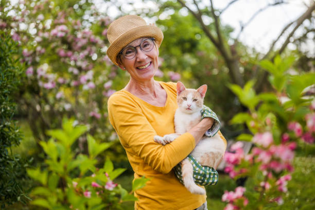 Senior woman holding cat while gardening