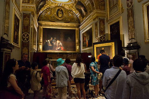 Valletta, Malta - 17 June 2023: Tourists in the sacristy room inside the Valletta co-cathedral in Malta where the two paintings by Caravaggio are exhibited: the beheading of Saint John the Baptist and Saint Jerome writing