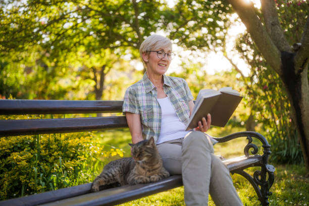 Senior woman reading book and spending time with her cat