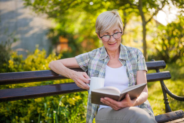 istock Senior woman reading book and drinking coffee 2149521618