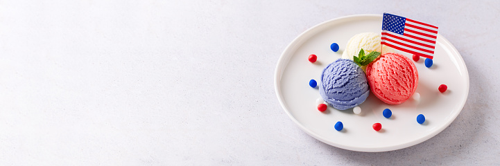 Patriotic colors ice cream scoops with American flag on white plate, Red, white and blue ice cream for 4th of July, web banner