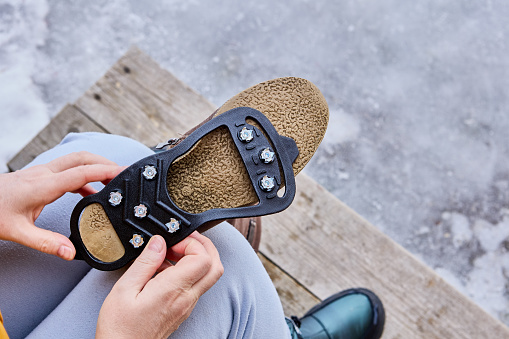 Attaching rubber lining with spikes to the sole of winter boots to improve traction and prevent slipping during icy conditions.