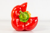 A red paprika is cut in half and has a green stem