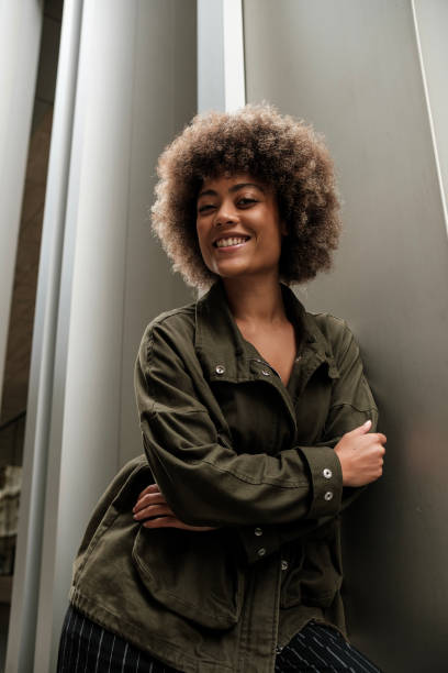 istock Mixed race curly woman leaning on metallic wall. 2149525800