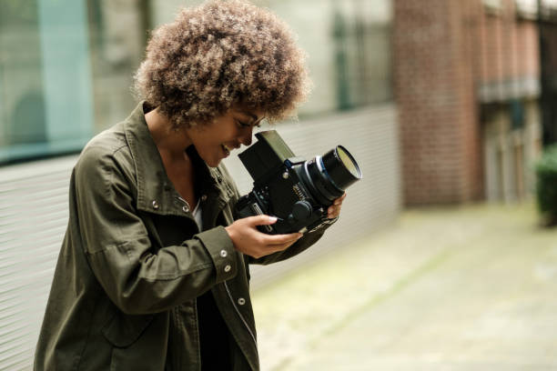 istock Enthusiastic attractive woman using an analog camera outdoors. 2149525857