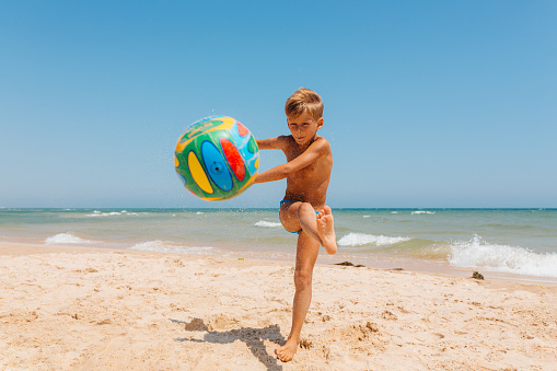 Boy having fun playing and dribbling with walleyball on the beach in the beautiful Algarve Portugal region