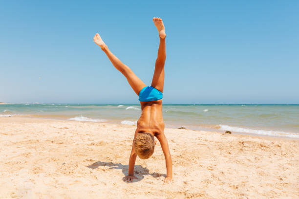 Boy having fun making some gymnastic exercise on the beach in Algarve region Portugal