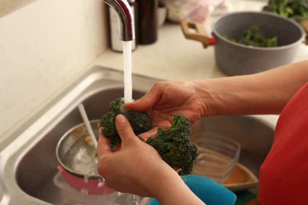 istock Washing fresh broccoli leaves in kitchen 2149534673
