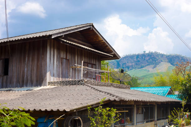 Weathered simple wooden house in small town  in landscape around Pang Kha in north Thailand with Royal Development Center and coffee plantations in mountains around Phayao. Area betwen Ban Hae and Pha Changf Noi  close to Pang Kha Royal Project And Development Centre. In background are mountains.