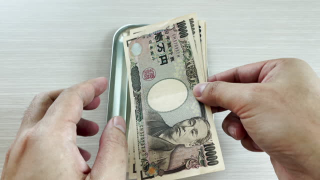 Hands count yen and place them in a tray for change for shopping or business and travel.