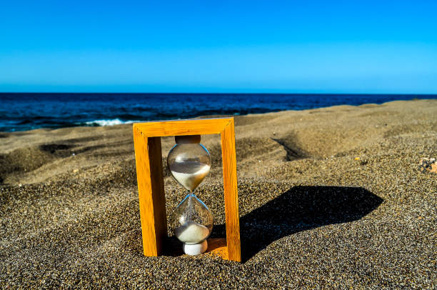 istock A sand timer is on the beach, with the sand timer showing the time as almost up 2149537464