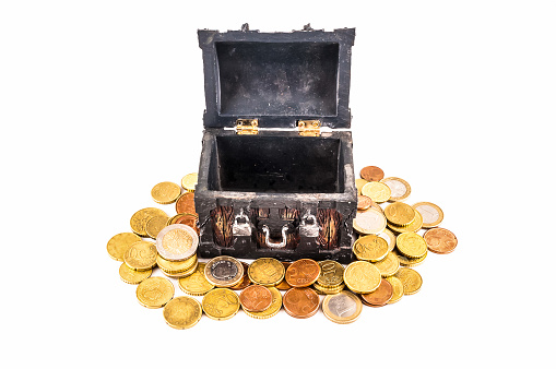 A small black box with gold coins on top of it. The coins are scattered around the box, with some of them being larger and others smaller. Concept of wealth and abundance