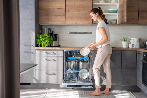 A woman removes clean ceramic dishes from the dishwasher. Household and useful technology concept. A woman removes clean ceramic dishes from the dishwasher. Household and useful technology concept. High quality photo. dishwasher stock pictures, royalty-free photos & images