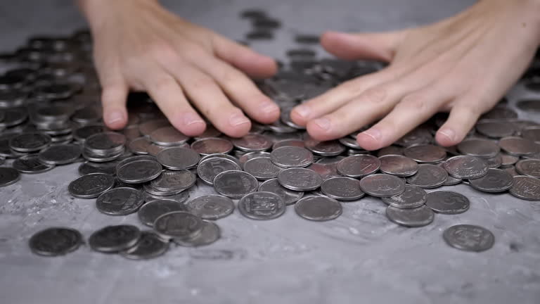 Greedy Female Hands are Moving a Pile of Scattered Ukrainian Coins on Table