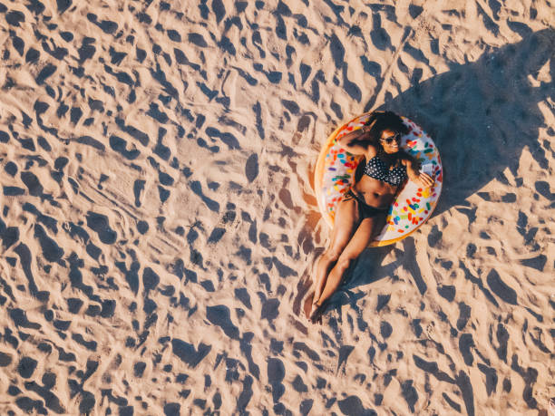 Smiling woman on beach holiday sunbathing and taking selfie