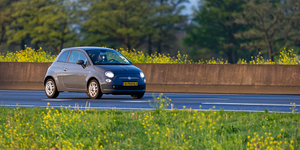 Wierden, Twente, Overijssel, Netherlands, april 21st 2024, daytime front/side view close-up of a Dutch gray 2010 Fiat 500 driving on the Dutch A35 highway at Wierden - the 500 is a popular city car made by Italian car manufacturer Fiat since 2007 (a retro style remake from the original 500 model that was made from 1957-1975), the A35 is a 76 kilometers long highway in the east of the country connecting Enschede with Wierden