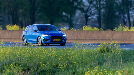 Wierden, Twente, Overijssel, Netherlands, april 21st 2024, daytime front/side view close-up of a Dutch blue 2019 Ford 4th generation Focus hatchback driving on the Dutch A35 highway at Wierden - the Focus is made by American car manufacturer Ford Motor Company since 1998, the A35 is a 76 kilometers long highway in the east of the country connecting Enschede with Wierden
