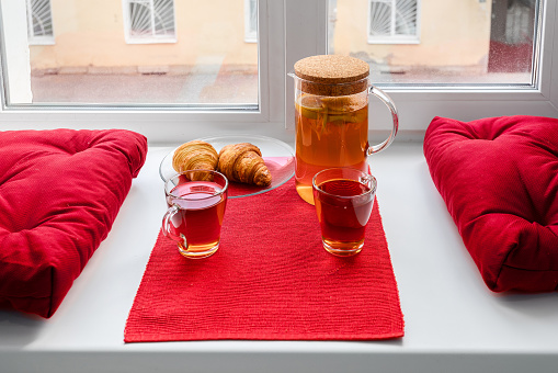 Tea and croissants on a windowsill, a cozy snack with a view from the window.