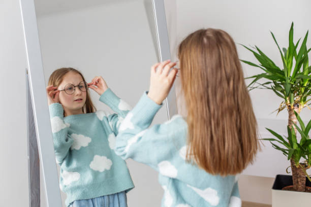 istock Morning routine. Child Adjusting New Glasses Looking in Mirror. Morning preparation before school. 2149546639