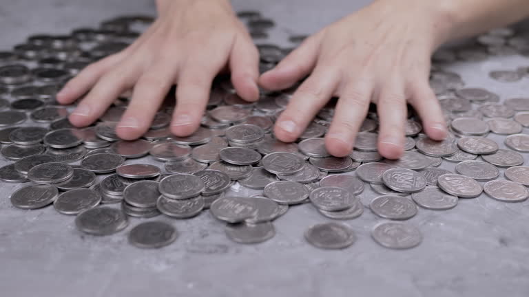 Greedy Female Hands are Stirring a Pile of Scattered Ukrainian Coins on Table